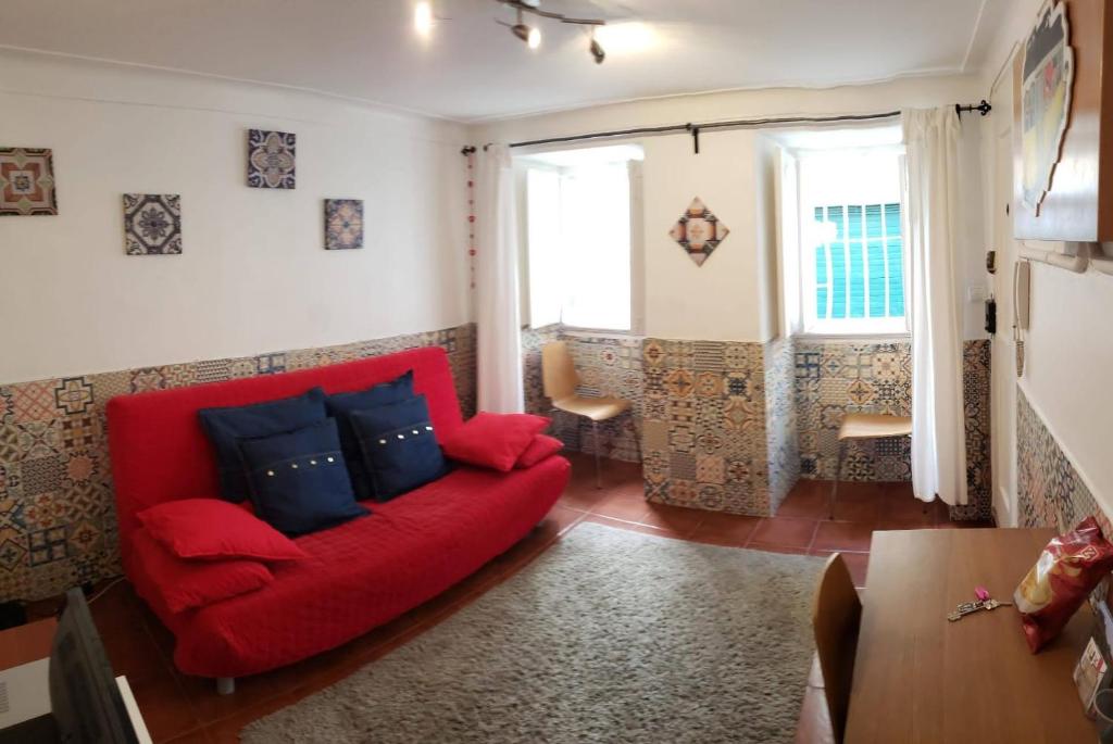 een woonkamer met een rode bank en 2 ramen bij Lisbon City Centre Apartment in Lissabon