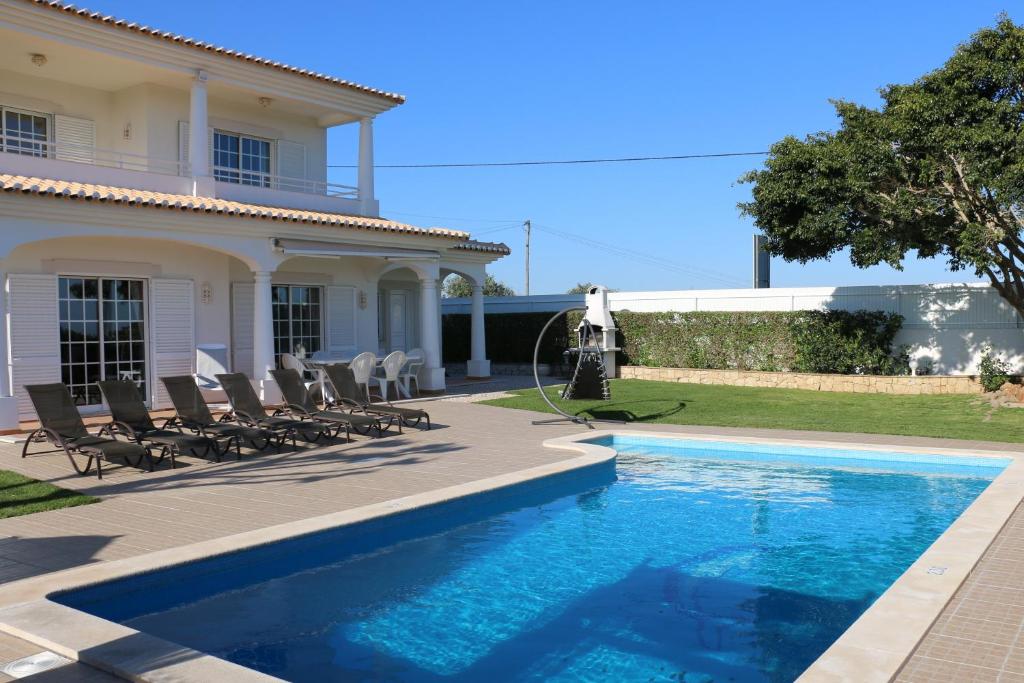 a villa with a swimming pool in front of a house at Casa Alves - Villa with private heated swimming pool in Olhos de Água