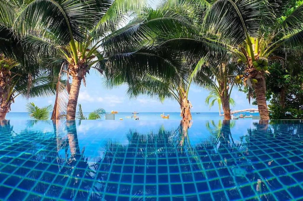 - une piscine bordée de palmiers et une vue sur l'océan dans l'établissement Seashell Resort Koh Tao-SHA Plus, à Koh Tao