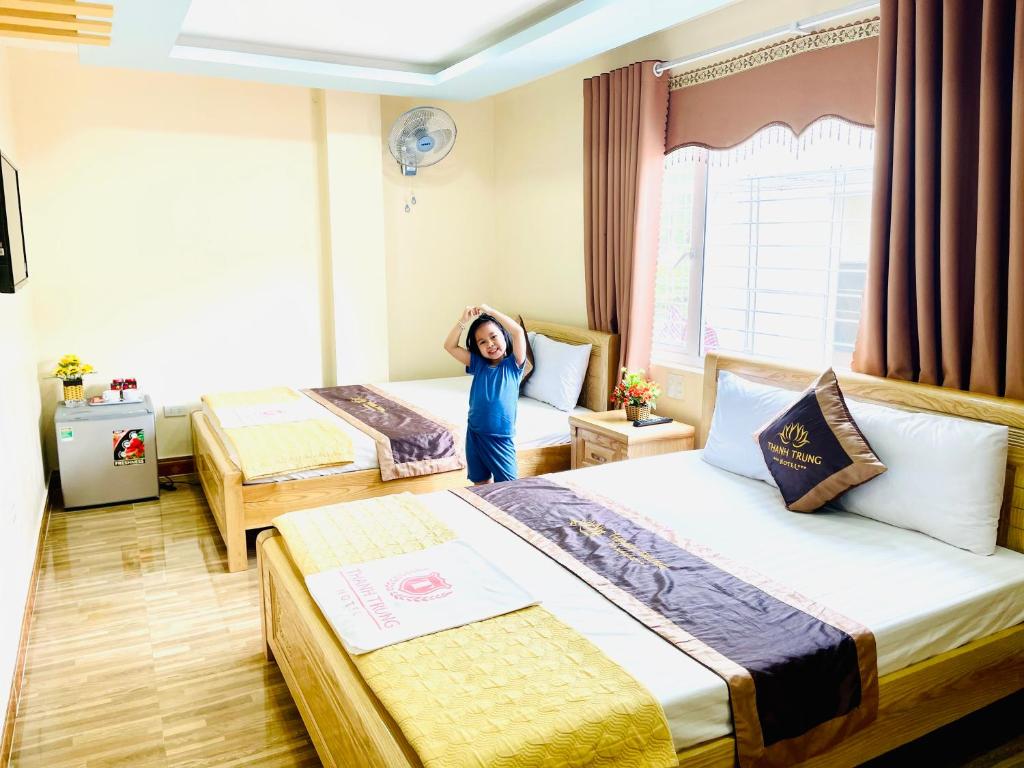 uma menina em pé num quarto de hotel com duas camas em Thanh Trung Hotel em Ilha de Cát Bà