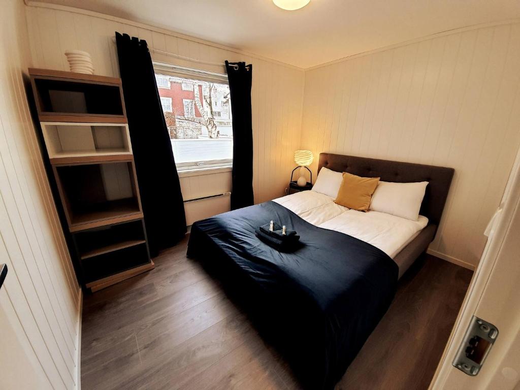 a bedroom with a bed with a black blanket and a window at Bnb Central Apartment 5 Downtown Stavanger Stavanger in Stavanger