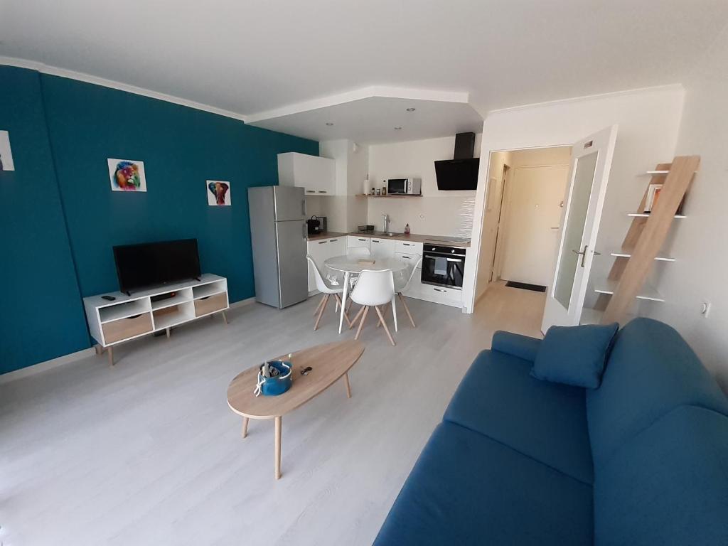 uma sala de estar com um sofá azul e uma mesa em Studio Centre - Tout Confort - Tout à pied em La Baule