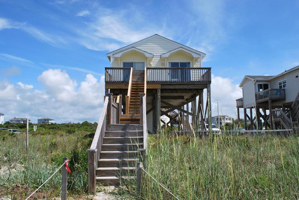 a house on the beach with stairs leading to it at 1 Anchors Away Oceanfront in Holden Beach