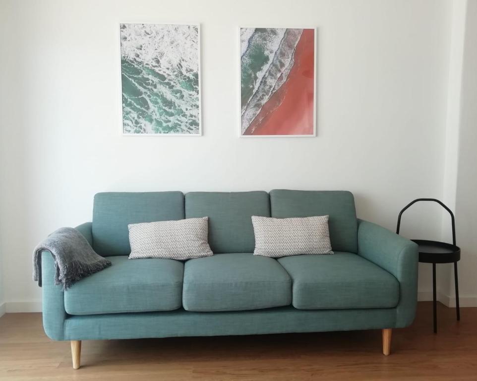 a green couch in a living room with two pictures at Sol Da Caparica in Costa da Caparica