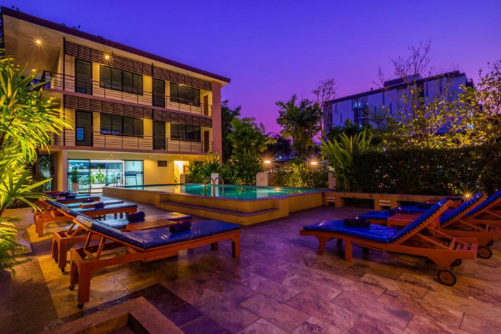A landscaped pool terrace is staged with rows of wooden loungers at dusk.