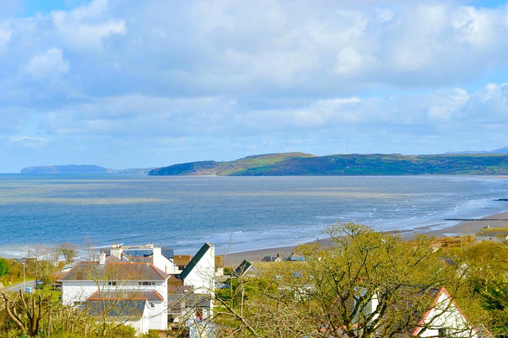 a view of a beach with a house and the ocean at Beach View in Benllech
