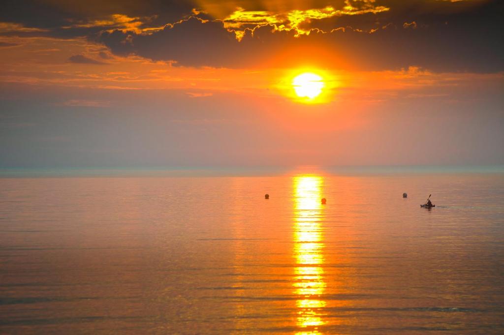 a person in a boat in the ocean at sunset at Beach View in Benllech