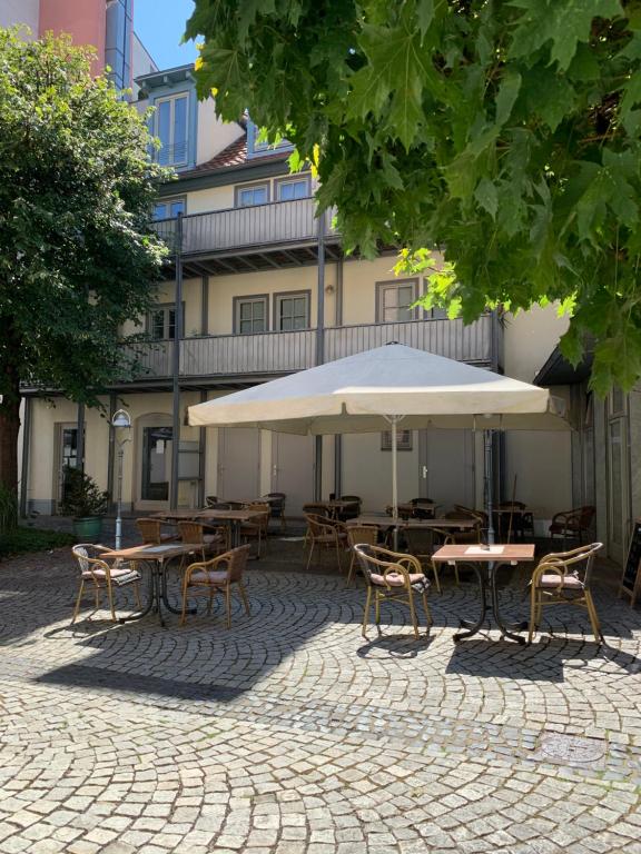 eine Terrasse mit Tischen, Stühlen und einem Sonnenschirm in der Unterkunft Altstadt, FEWO im Markthof am Dom in Erfurt