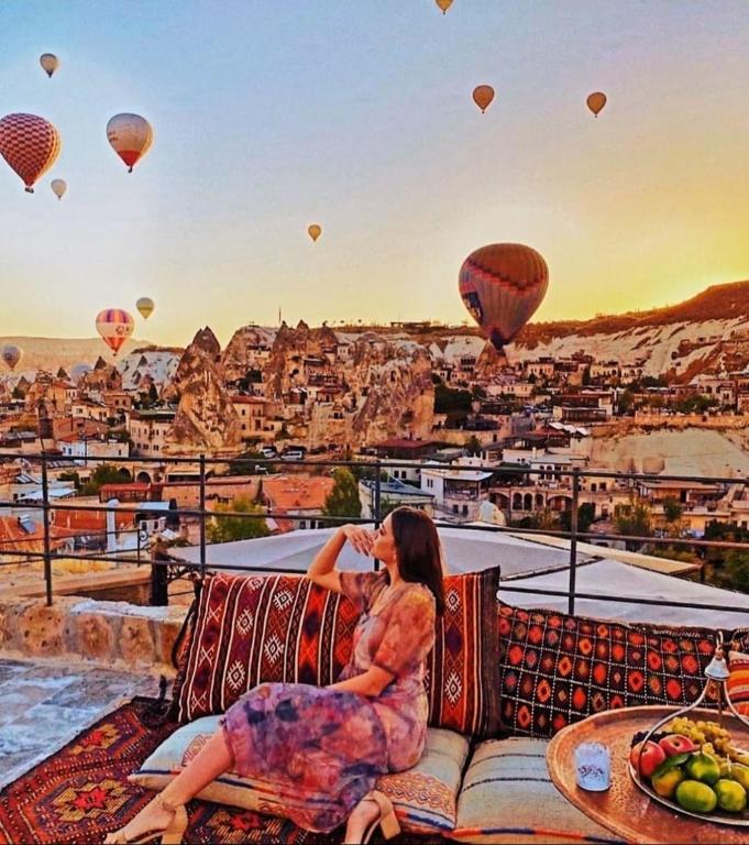 a woman sitting on a couch watching hot air balloons at Tekkaya Cave Hotel in Goreme