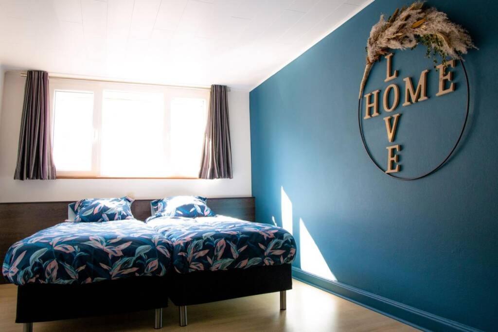 een slaapkamer met een blauwe muur met een bed en een spiegel bij Au Comilfo in Malmedy