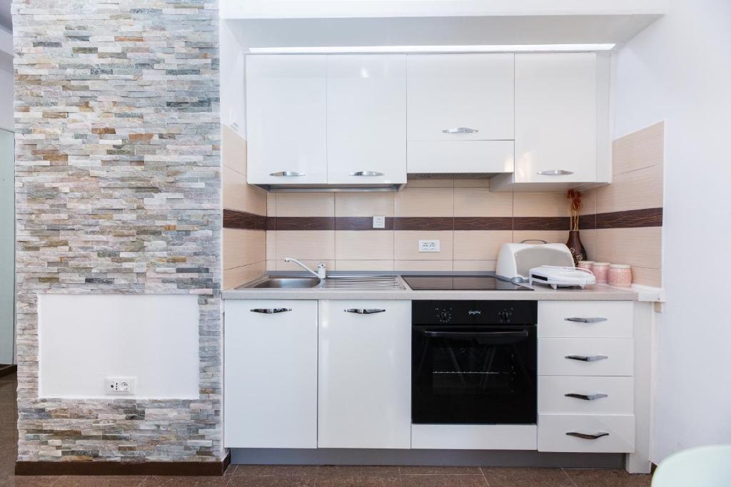 eine Küche mit weißen Schränken und einem schwarzen Backofen in der Unterkunft Kastela Agneza Apartment (2+1) near SplitAirport in Kaštela