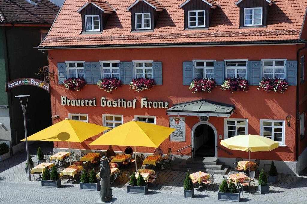 un bâtiment avec des tables et des parasols devant lui dans l'établissement Brauereigasthof Krone, à Tettnang