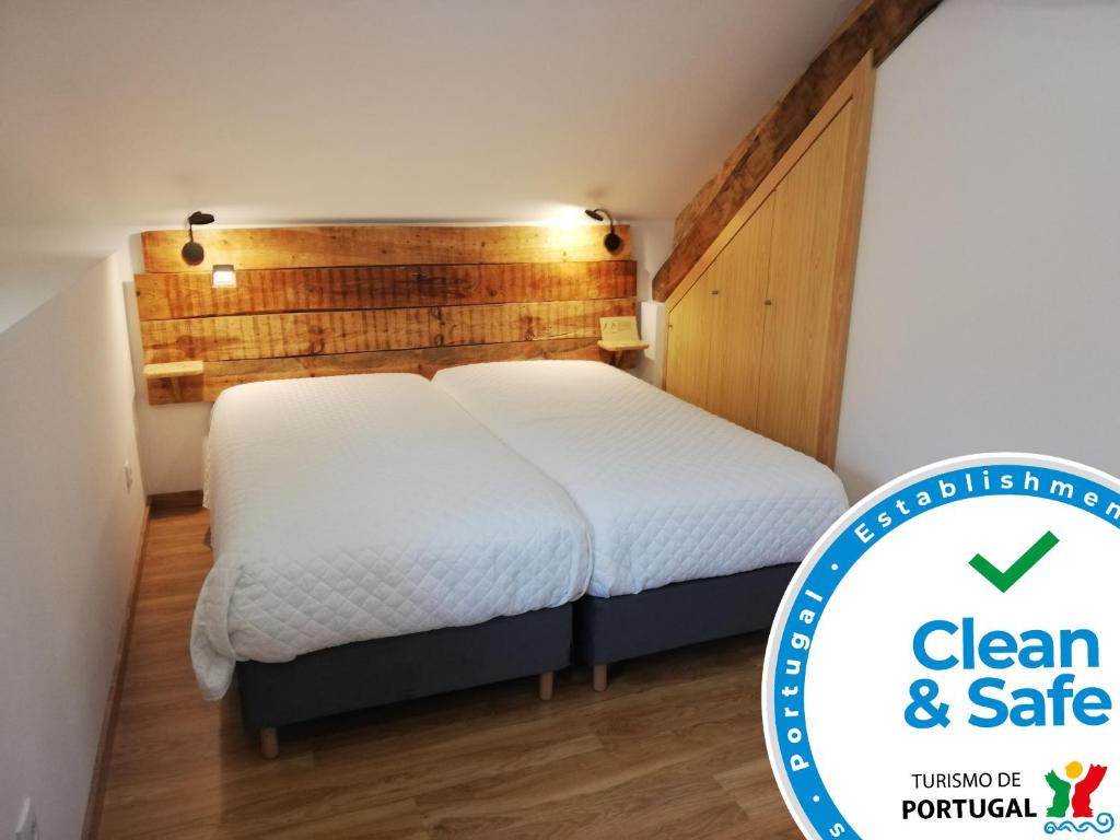 a bedroom with a white bed and a wooden wall at Sambuc'asa - Serra da Estrela in Sabugueiro