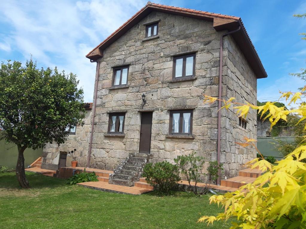una vecchia casa in pietra con un albero di fronte di Casa Camino Santiago-Fisterra ad Amés
