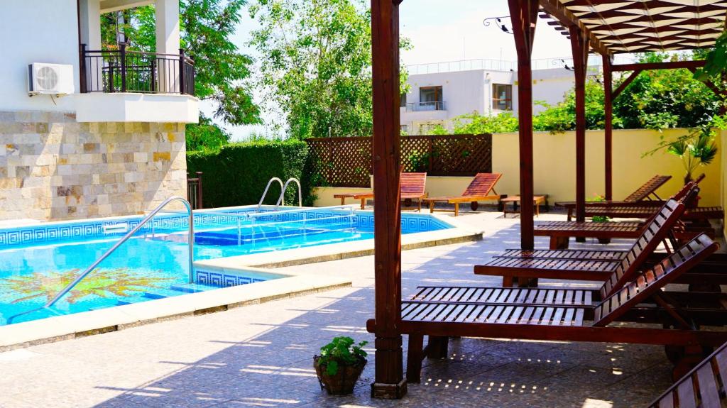 a swimming pool with two benches and an umbrella at Бяла Виста Бийч Апартментс A - Byala Vista Beach Apartments A in Byala