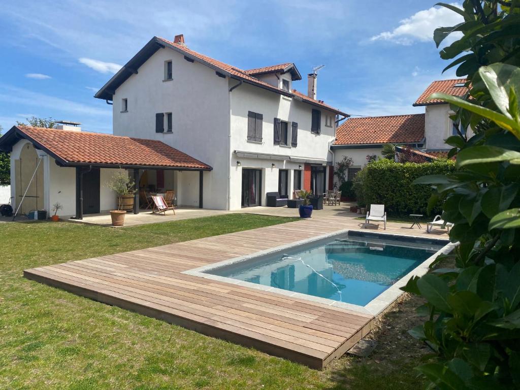 a backyard with a wooden deck and a swimming pool at Hiru Alabak - Maison à Biarritz, piscine, jardin, 8 personnes in Biarritz