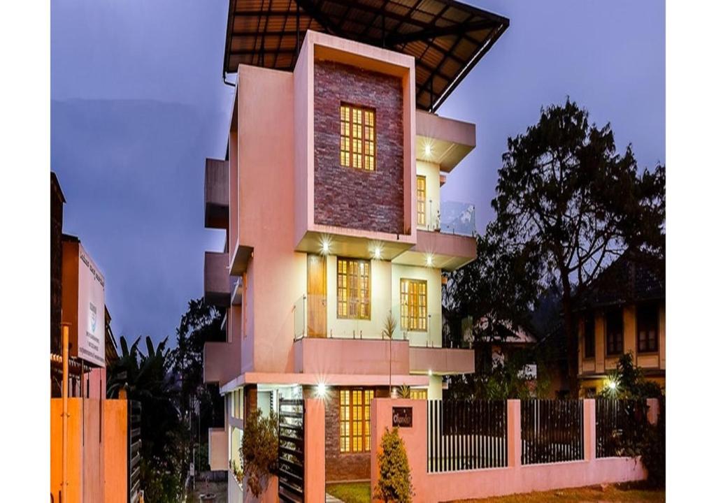 a large pink building with lights on it at MySpace Express Oleander Service Apartments in Madikeri