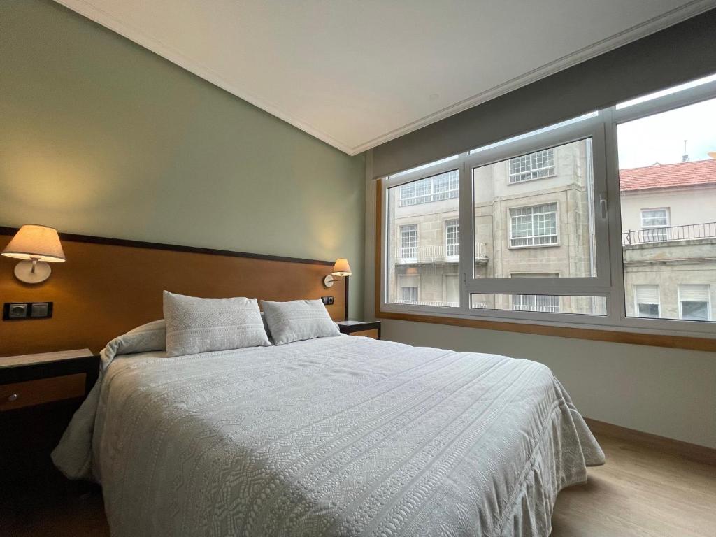 a bedroom with a bed and a large window at Aparthotel Arenteiro in Carballino