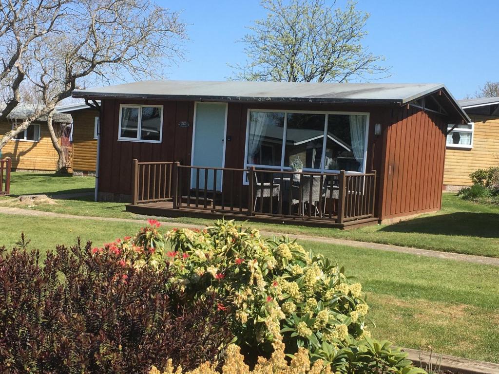 eine kleine Hütte mit einer Veranda und einer Terrasse in der Unterkunft Chalet Thirty Two in Seaton