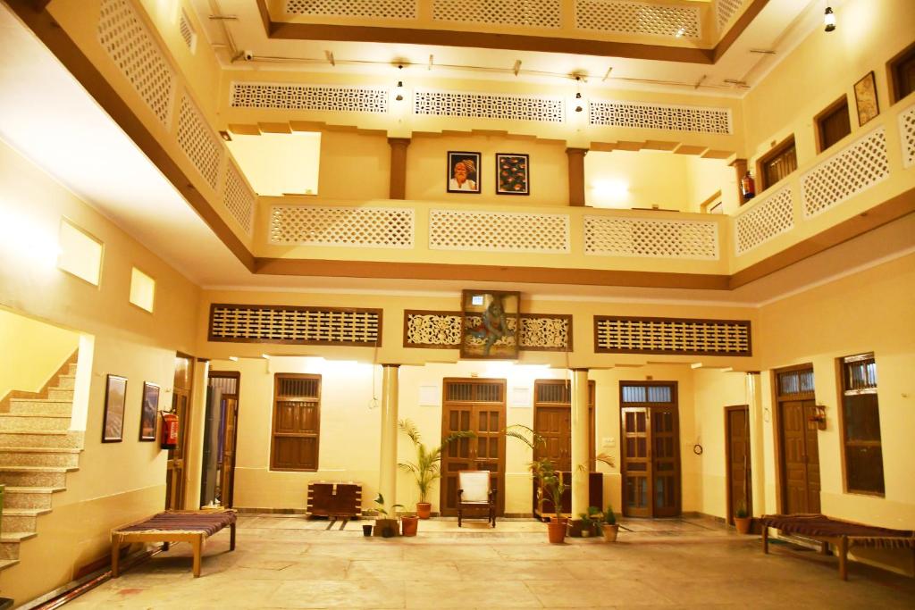 a lobby with benches and tables in a building at Gobind Bhawan Heritage Hotel in Haridwār