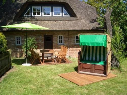 ein Haus mit einem grünen Regenschirm, einem Tisch und Stühlen in der Unterkunft 1000 - Lüntsches Schloss Riepsdorf in Thomsdorf