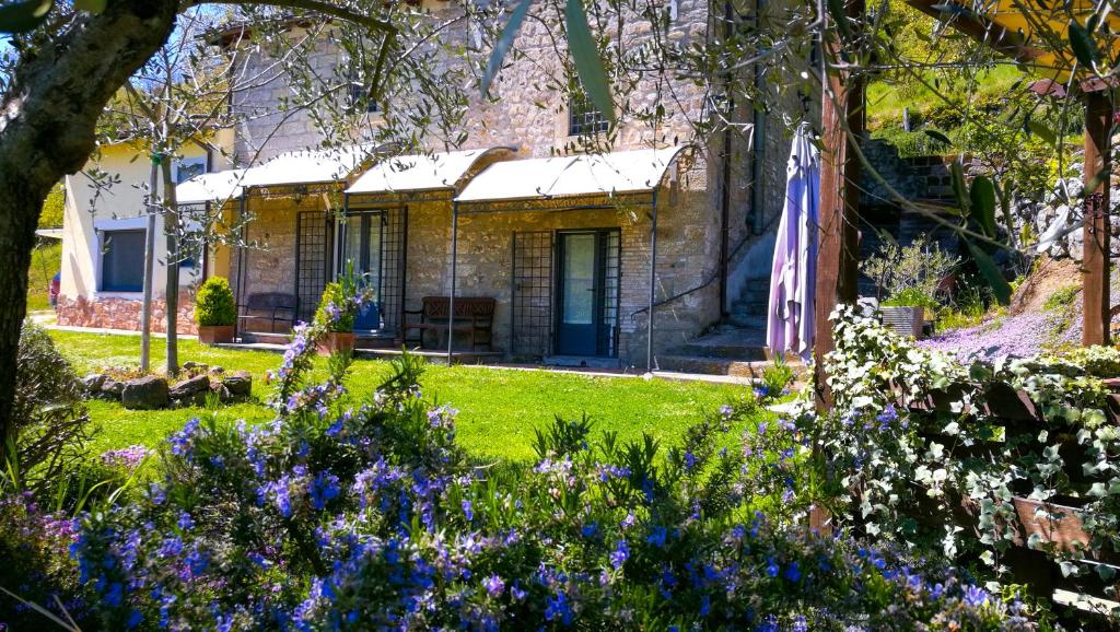a stone house with a garden with purple flowers at Podere Pontepietra in Soriano nel Cimino