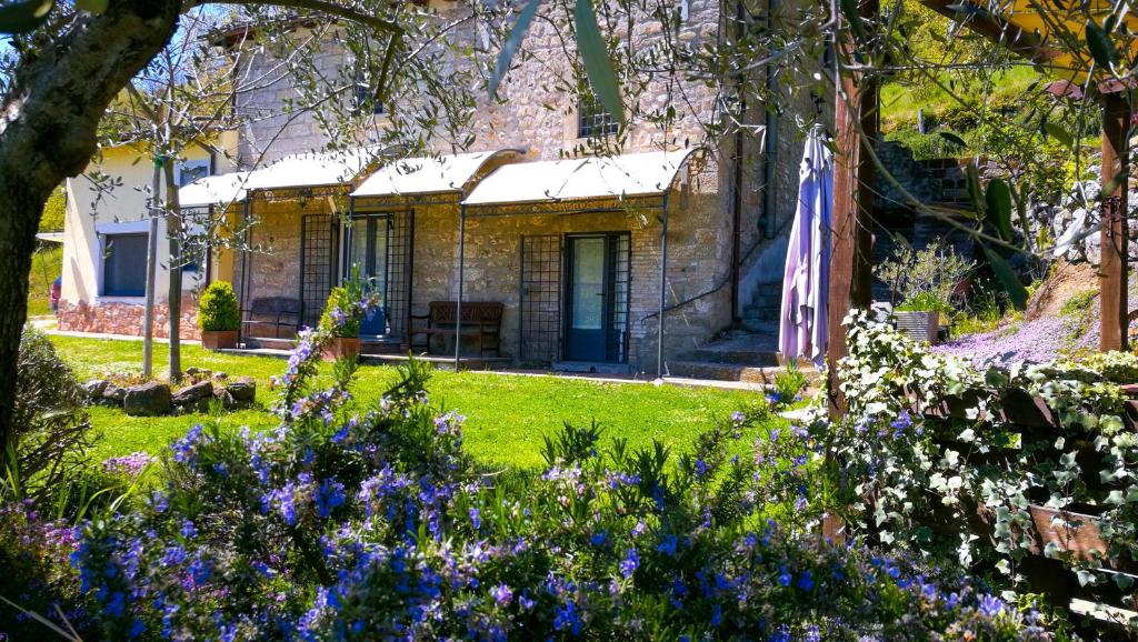 uma casa de pedra com um jardim com flores roxas em Podere Pontepietra em Soriano nel Cimino