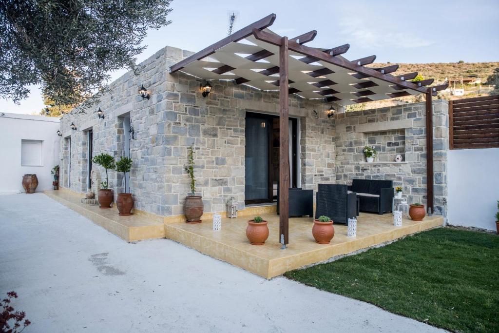 una casa de piedra con pérgola y macetas en Villa Mira en Kamilari