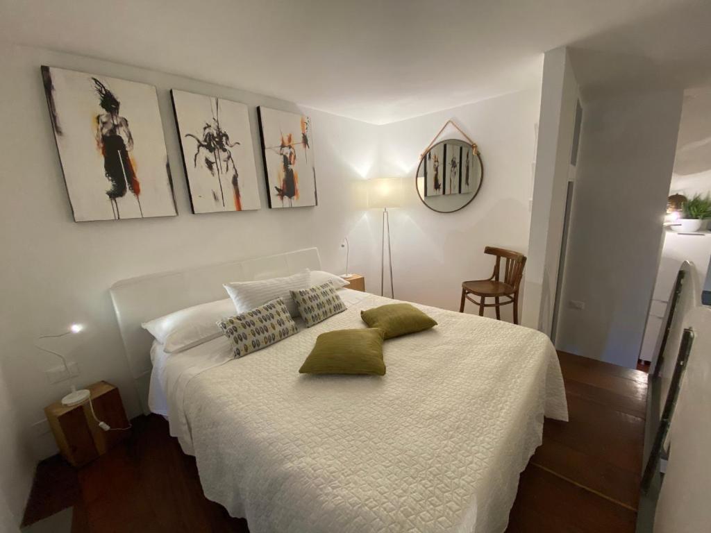 a bedroom with a white bed with green pillows at La Verde di Vernazza - Art Studio - AC&WiFi - Vernazzarentals in Vernazza