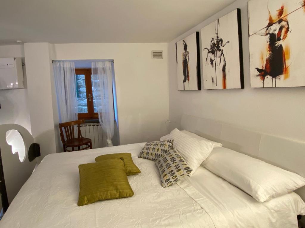 a white bed in a room with pictures on the wall at La Verde di Vernazza - Art Studio - AC&WiFi - Vernazzarentals in Vernazza