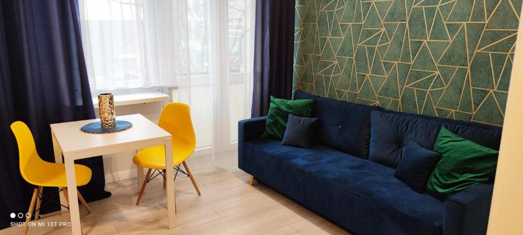 een woonkamer met een blauwe bank en een tafel bij Apartament Fifi in Warschau
