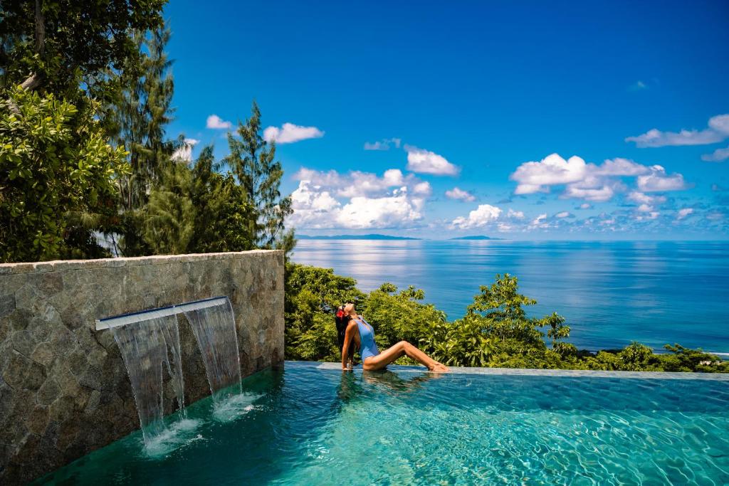 Glacis的住宿－AQUA Boutique Hotel，坐在游泳池俯瞰大海的女人
