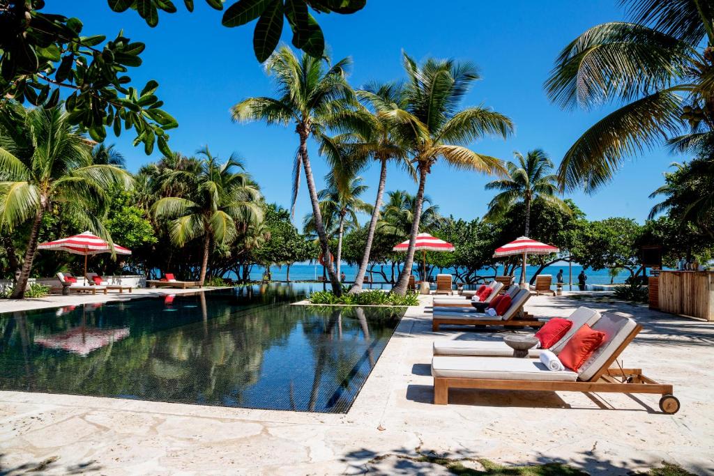 una piscina en el complejo con tumbonas y palmeras en Itz'ana Resort & Residences en Placencia Village