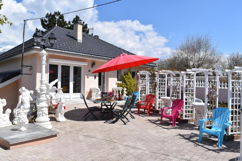 un patio con sillas, una mesa y una sombrilla en Gîte Au Clair Matin ,la Mure, les passerelles Monteynard, en Pierre-Châtel