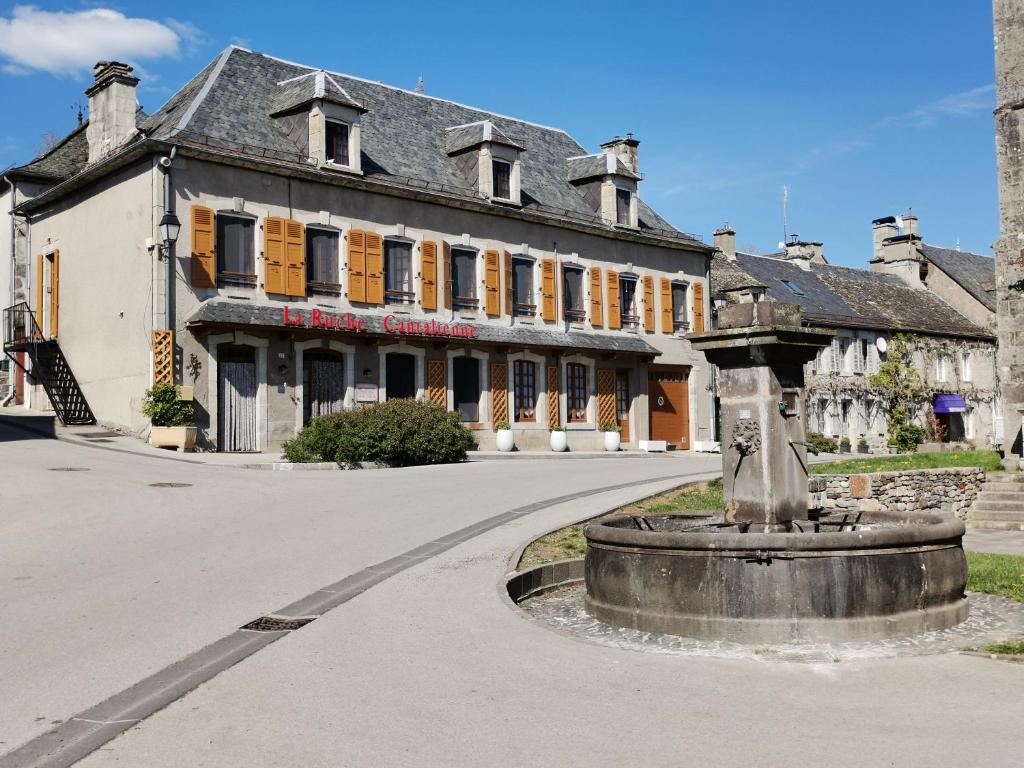 a building with a fountain in the middle of a street at La Ruche Cantalienne in Saint-Étienne-de-Chomeil