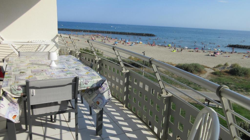 un balcon avec une table et des chaises et une plage dans l'établissement Appartement 1ère ligne très belle vue mer Rochelongue Cap d'Agde, au Cap d'Agde