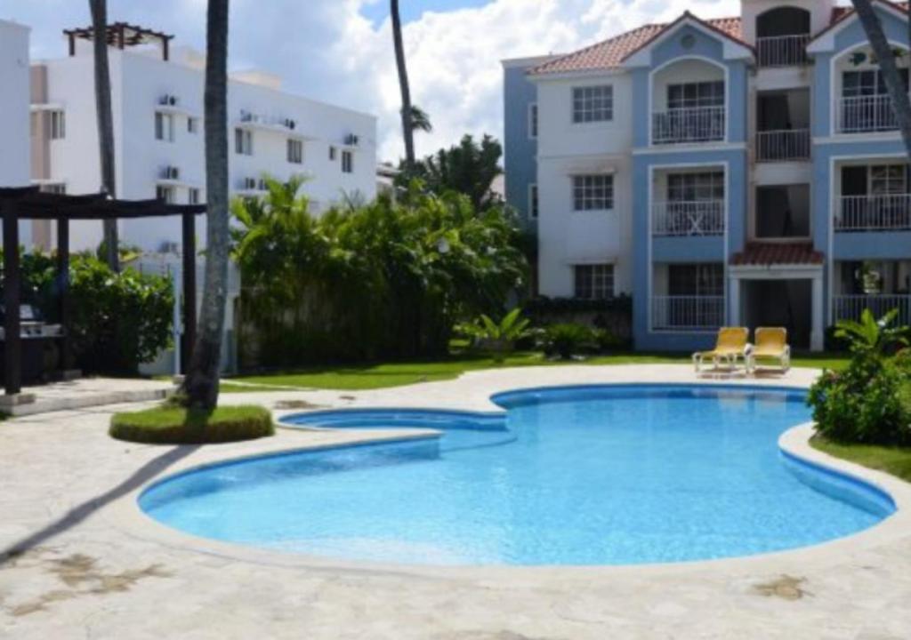 a swimming pool in front of a building at Apartamento Vacacional con Piscina para Familias en Punta Cana in Punta Cana