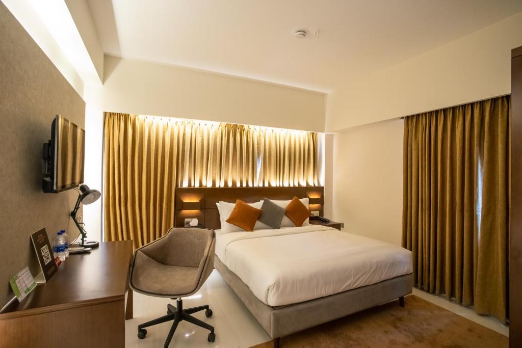 a bedroom with a bed and a desk and a chair at Jatra Flagship Khulna City Centre in Khulna