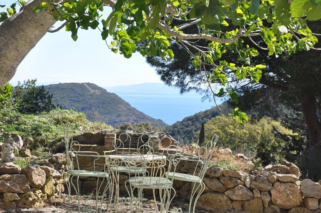 een tafel en stoelen op een rotswand bij Ferienhaus Elba Porto Azzurro mit Panorama und Garten in Capo D'Arco