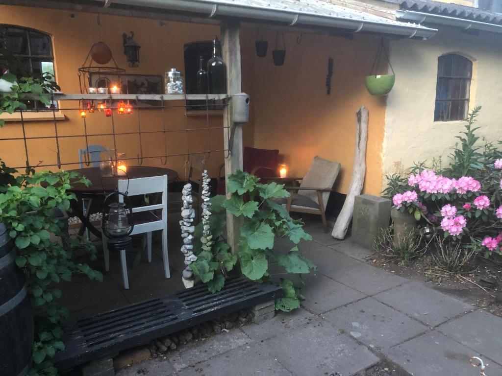um pátio com uma mesa, cadeiras e flores em Retro bolig - fyldt med hygge! Ingen luksus em Kolind