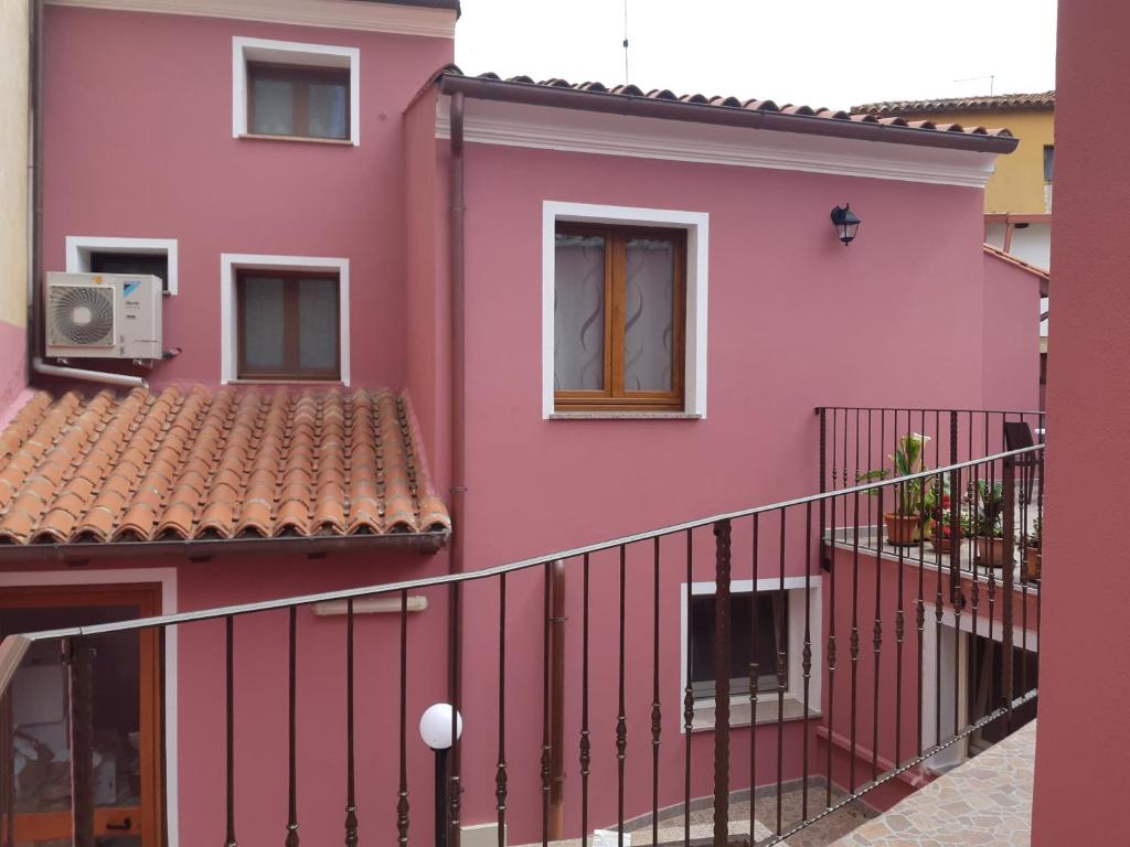 różowy budynek apartamentowy z balkonem w obiekcie B&B La Genuina w mieście Guspini