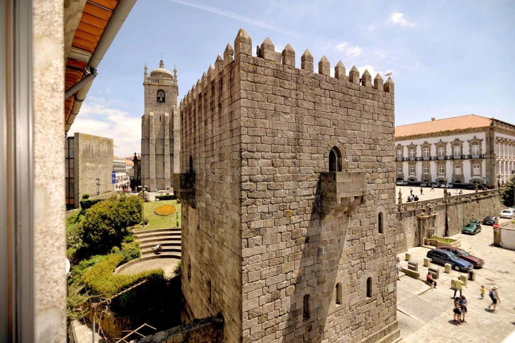 un edificio alto de ladrillo con una torre de reloj en Cathedral Design Apartments, en Oporto