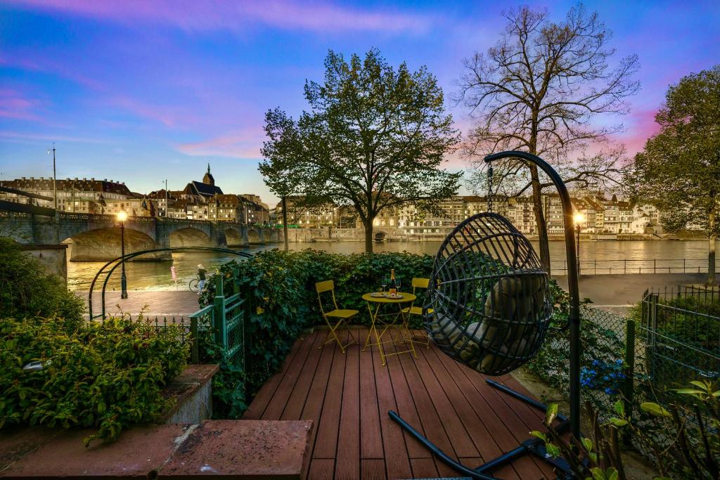 a wooden deck with a table and chairs next to a river at Stadtwohnung am Wasser I Terrasse mit Rheinblick I NETFLIX I APPLE TV in Basel