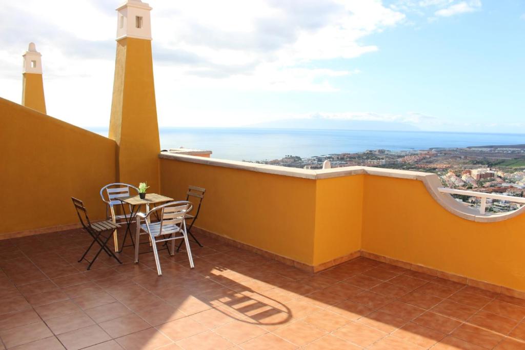 d'un balcon avec une table, des chaises et un phare. dans l'établissement Holiday home with a Serene Ocean and Mountain View, à Adeje