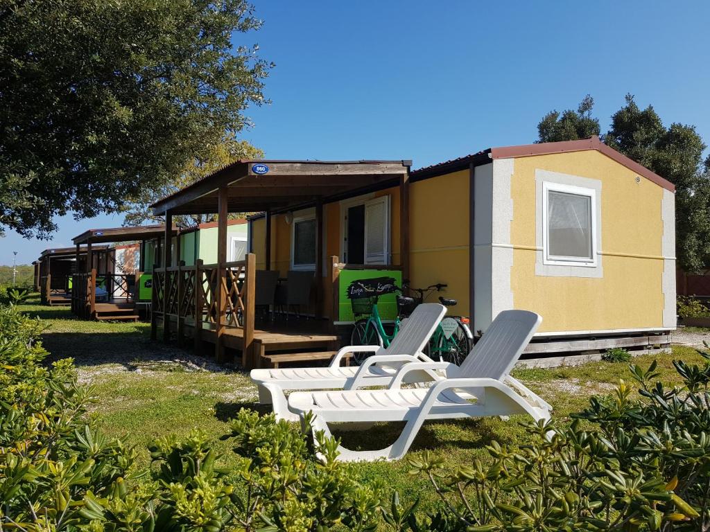 kilka krzeseł ogrodowych i mały domek w obiekcie Naturist Mobile Homes Eden in FKK Ulika w Poreču