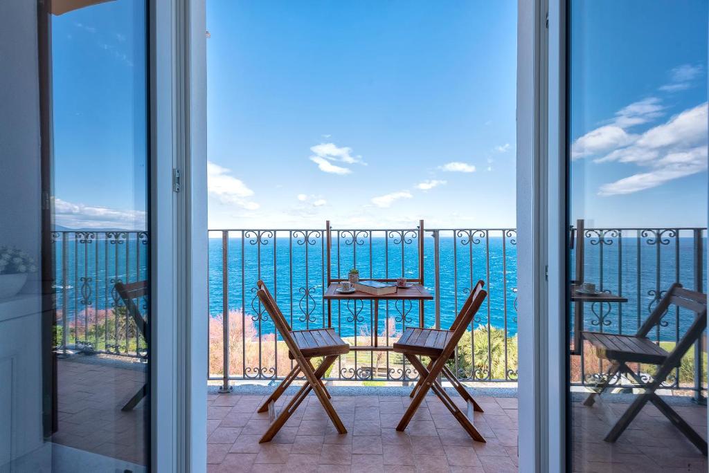 una mesa y sillas en un balcón con vistas al océano en “CIELO E MARE”, CASETTA NEL CUORE DEL BORGO ANTICO / “SKY & SEA”, CHARMING IN THE HEART OF OLD VILLAGE en Castelsardo