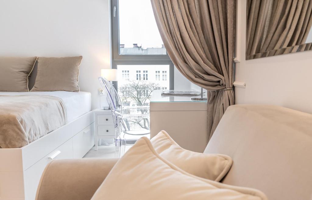 a bedroom with a bed and a chair and a window at BE IN GDANSK Apartments - DŁUGIE OGRODY in Gdańsk