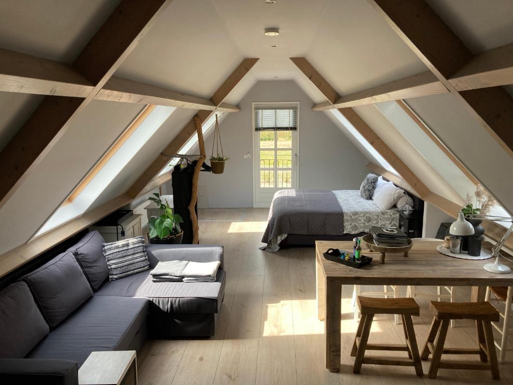 a attic room with a bed and a couch and a table at BBOosterweg3 Studio in Heemskerk