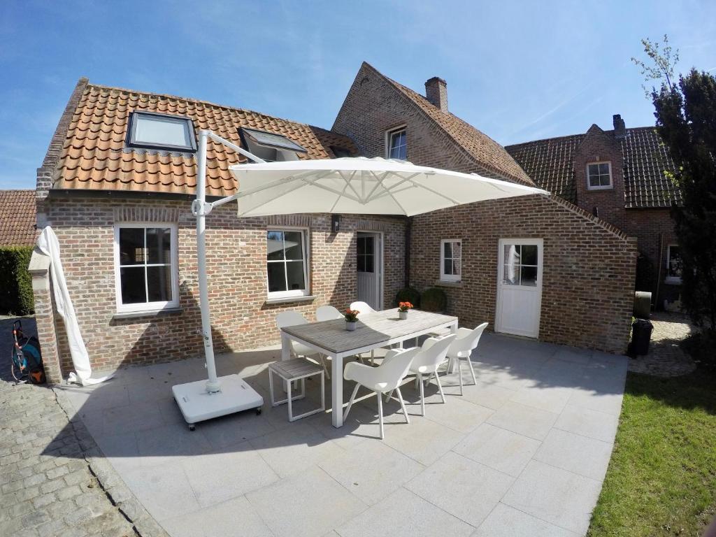 a patio with a table and an umbrella at Chaleureux in Wenduine