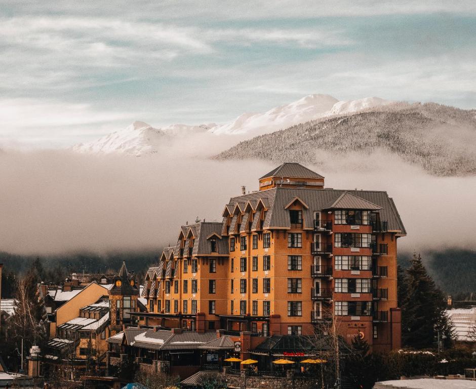 un grand bâtiment avec une montagne en arrière-plan dans l'établissement Sundial Hotel, à Whistler